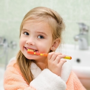 Young child smiling and brushing her teeth.